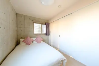 a bedroom with a white bed with pink pillows at DeLIGHT HOTEL in Tokyo