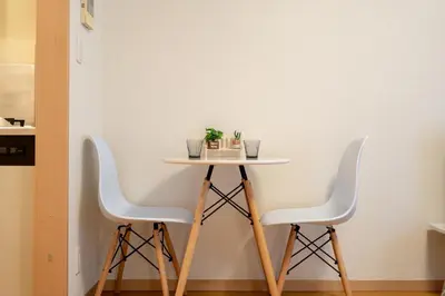 a small table with three white chairs in a room at Belle Lead in Tokyo