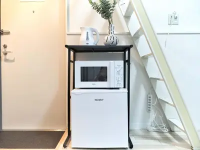 a microwave on top of a refrigerator next to a staircase at \u65b0\u5bbf\u4e2d\u5fc3\u5546\u5708-\u65b0\u5927\u4e45\u4fdd\u5f92\u6b654\u5206-\u65b0\u5bbf\u5f92\u6b6510\u5206-2Room-Max4P in Tokyo