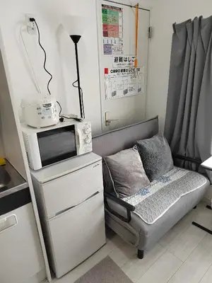a small room with a chair and a microwave at \u6771\u4eac\u5929\u7a7a\u4e4b\u5bb6\u6c11\u5bbf201\u72ec\u7acb\u516c\u5bd3 \u72ec\u7acb\u536b\u6d74 in Tokyo