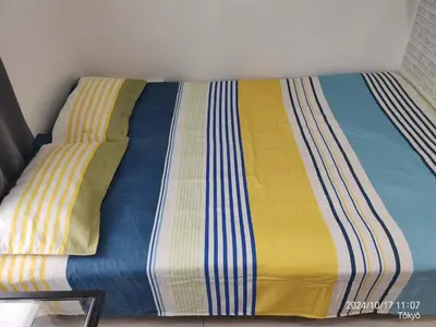 a bed with a yellow and blue blanket on it at \u6771\u4eac\u5929\u7a7a\u4e4b\u5bb6\u6c11\u5bbf201\u72ec\u7acb\u516c\u5bd3 \u72ec\u7acb\u536b\u6d74 in Tokyo
