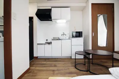 a kitchen with white cabinets and a table in a room at nakano102 in Tokyo