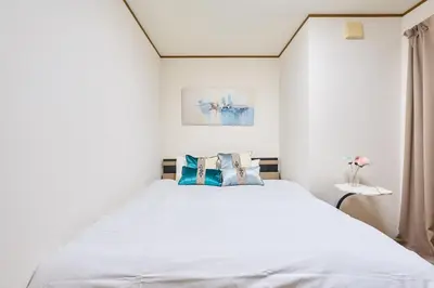 a bedroom with a white bed with blue pillows at JR ChuoLine Aasagaya station 5min,Shinjuku 8min Max15pp 2WC in Tokyo