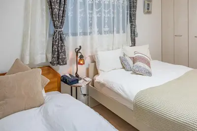 a bedroom with two beds and a window at 3 minutes walk to the station, direct to Ikebukuro, two-story house with a garden in Tokyo