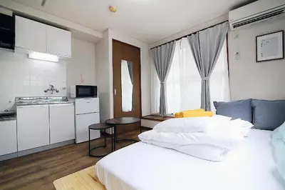 a bedroom with a white bed and a kitchen at nakano102 in Tokyo