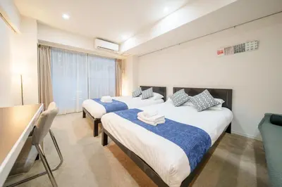 two beds in a room with a table and chairs at Pangoo Shinagawa Room 502 - Vacation STAY 99413v in Tokyo