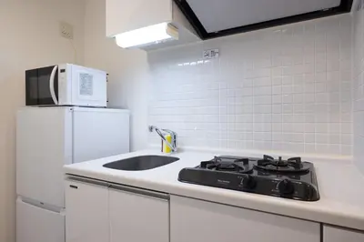 a kitchen with a stove and a white refrigerator at \u30ec\u30b8\u30c7\u30a3\u30a2\u4e2d\u843d\u5408a in Tokyo