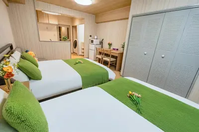 two beds in a room with a kitchen and a table at Room 202 Nishi-Shinjuku Gochome 9 minutes walk 40 square meters Sleeps up to 6 people in Tokyo