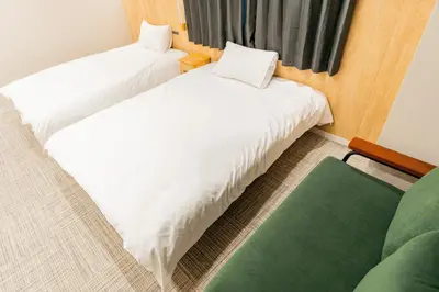 two beds in a room with a green couch at Tokyo Skytree\u96fb\u8eca3\u5206 \u79cb\u8449\u539f\u307e\u30677\u5206 \u6d45\u8349\u6a4b\u307e\u30674\u5206 \u30ad\u30c3\u30c1\u30f3\u5b8c\u5099 \u9326\u7cf8\u753a\u99c5 \u5bdd\u5ba4\u4e8c\u3064 202\u90e8\u5c4b in Tokyo