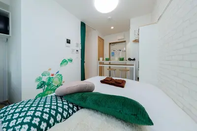 a bed with green and white pillows on it at Zenith Shinjuku Hinoki by Tranova in Tokyo