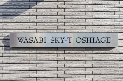 a sign on the side of a brick wall at Wasabi Sky Oshiage \u62bc\u4e0a\u99c5\u5f92\u6b69\u30a2\u30d1\u30fc\u30c8 in Tokyo