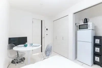 a small white kitchen with a table and a microwave at Flora Maison Kamiochiai by Tranova in Tokyo