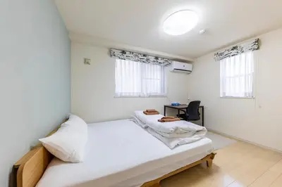a white bedroom with a bed and a desk at Jin's Place - 15m to Haneda & Shinagawa in Tokyo