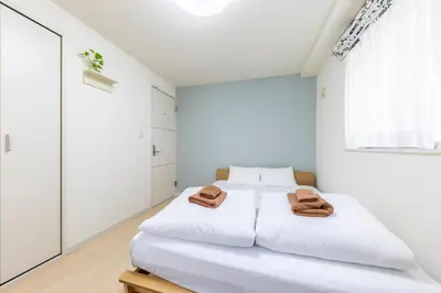 a white bedroom with a bed with two towels on it at Jin's Place - 15m to Haneda & Shinagawa in Tokyo
