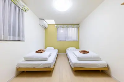 two beds in a small room with a window at Jin's Place - 15m to Haneda & Shinagawa in Tokyo