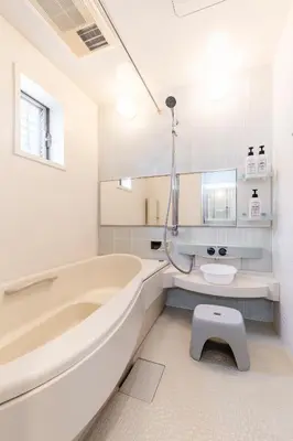 a white bathroom with a tub and a toilet at Jin's Place - 15m to Haneda & Shinagawa in Tokyo