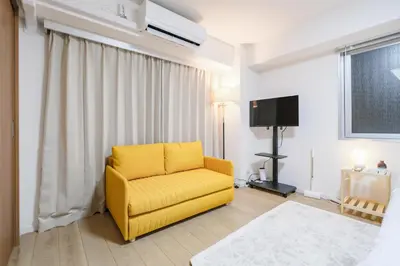 a yellow chair in a living room with a television at Shinjuku Raise OG House in Tokyo