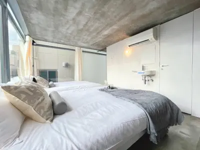 a bedroom with a large white bed with a concrete ceiling at Natsumezaka Room2 NM2 in Tokyo