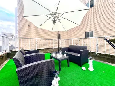 a patio with two chairs and a table with an umbrella at Shinjuku\u5927\u4e45\u4fdd3 in Tokyo