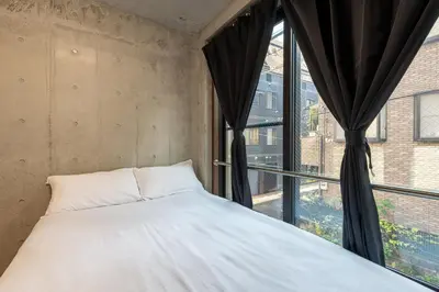 a bed in a room with a large window at \u53f0\u6771\u533a\u53f0\u6771\u3067\u5feb\u9069\u306a\u5bbf\u6cca\u3092\u6d45\u8349 \u4e0a\u91ce\u89b3\u5149\u306e\u62e0\u70b9\u306b 201 in Tokyo