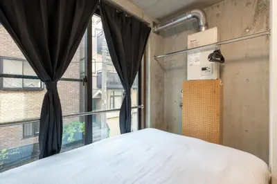 a bedroom with a bed in front of a window at \u53f0\u6771\u533a\u53f0\u6771\u3067\u5feb\u9069\u306a\u5bbf\u6cca\u3092\u6d45\u8349 \u4e0a\u91ce\u89b3\u5149\u306e\u62e0\u70b9\u306b 201 in Tokyo