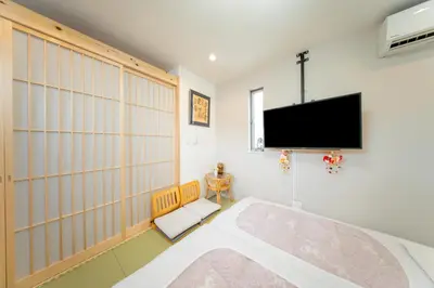 a bedroom with a flat screen tv on the wall at \u6c5f\u6238\u4e0b\u753a\u66ae\u3089\u3057\u4f53\u9a13 \u65b0\u7bc9\u4e00\u8ed2\u5bb6 \u6700\u59279\u540d \u6210\u7530\u79cb\u8449\u539f\u938c\u5009\u76f4\u901a \u5feb\u9069\u8a2d\u5099 in Tokyo