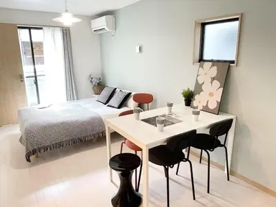 a small room with a bed and a table and chairs at COMMA HOUSE Kitaikebukuro 101 in Tokyo
