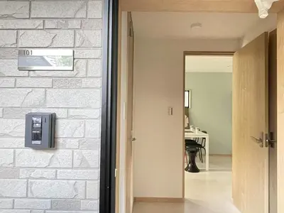 a hallway with a white brick wall and a door at COMMA HOUSE Kitaikebukuro 101 in Tokyo