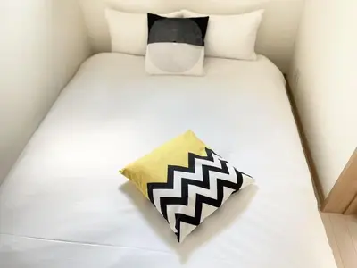 a bed with a black and white pillow on it at COMMA HOUSE Kitaikebukuro 101 in Tokyo