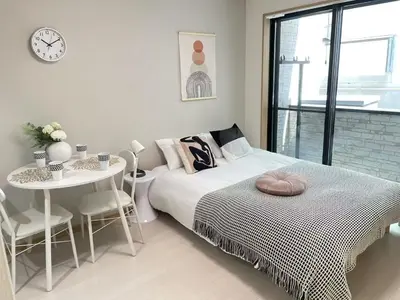 a bedroom with a bed and a table and a clock at COMMA HOUSE Kitaikebukuro 102 in Tokyo