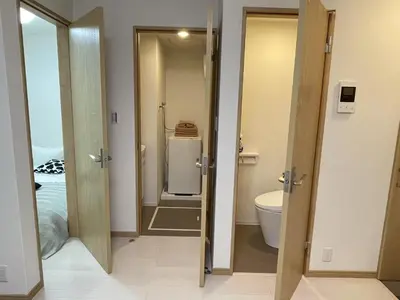 a bathroom with two open doors and a toilet at COMMA HOUSE Kitaikebukuro 102 in Tokyo