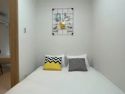 a bedroom with a white bed with two pillows at COMMA HOUSE Kitaikebukuro 103 in Tokyo