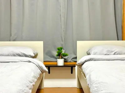 two beds with a plant on a table between them at Ikebukuro Sugamo\u99c5\u8fd1\u6700\u592710\u4eba\u53ef in Tokyo