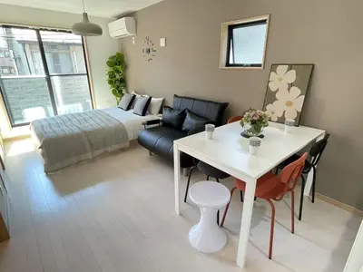 a living room with a bed and a white table at COMMA HOUSE Kitaikebukuro 201 in Tokyo