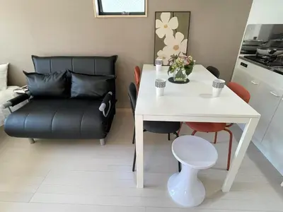 a living room with a white table and a black couch at COMMA HOUSE Kitaikebukuro 201 in Tokyo