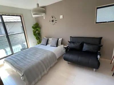 a bedroom with a bed and a leather chair at COMMA HOUSE Kitaikebukuro 201 in Tokyo