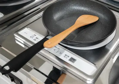 a frying pan with a wooden spoon on a stove at OHAYO AN asakusa in Tokyo