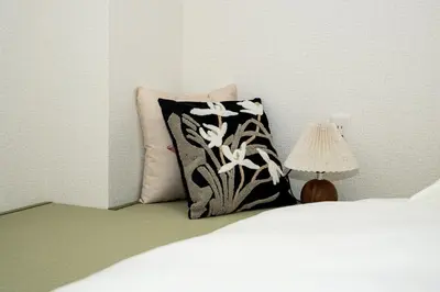 a bed with a black and white pillow and a lamp at OHAYO AN asakusa in Tokyo