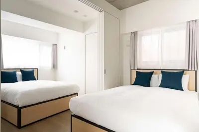 a bedroom with two beds with blue pillows at ASTiLE\u62bc\u4e0a in Tokyo