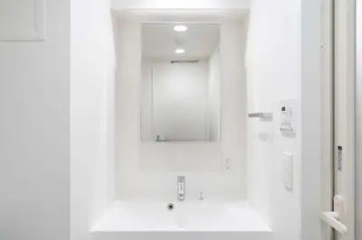 a white bathroom with a sink and a mirror at ASTiLE\u62bc\u4e0a in Tokyo