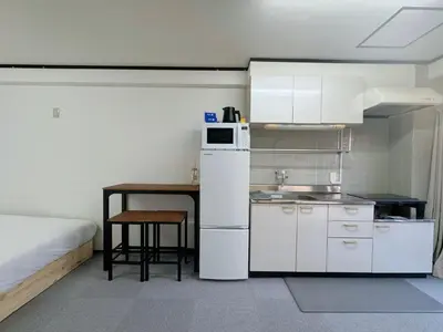 a small kitchen with a white refrigerator and a table at IKEBUKURO LoveSugamo \u4ea4\u901a\u4fbf\u5229 \u5c71\u624b\u7dda\u5de3\u9d28\u99c5\u5f92\u6b693\u5206 \u6c60\u888b\u99c54\u5206 2\u30fc4\u4eba \u30a8\u30ec\u30d9\u30fc\u30bf\u30fc WIFI \u65b0\u5bbf \u6e0b\u8c37 \u9280\u5ea7 \u6d45\u8349 \u9280\u5ea7 \u539f\u5bbf\u30a2\u30af\u30bb\u30b9\u4fbf\u5229 \u7a7a\u6e2f\u76f4\u901a in Tokyo