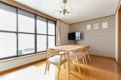 a dining room with a table and chairs and windows at NKm\u6625\u6c5f\u753a3\u4e01\u76ee in Tokyo