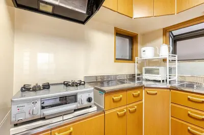 a kitchen with wooden cabinets and a stove at NKm\u6625\u6c5f\u753a3\u4e01\u76ee in Tokyo