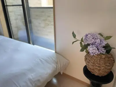 a vase filled with purple flowers sitting next to a bed at COMMA HOUSE Kitaikebukuro 202 in Tokyo