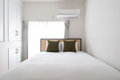 a bedroom with a large white bed with green pillows at \u4eac\u5cf63\u4e01\u76ee\u8cb8\u6238\u5efa in Tokyo