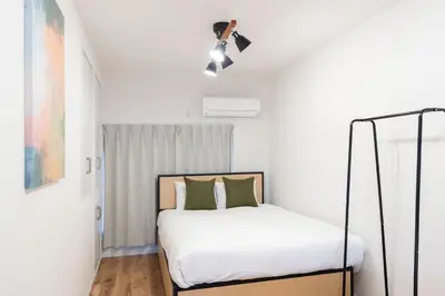 a bedroom with a bed with white sheets and green pillows at \u4eac\u5cf63\u4e01\u76ee\u8cb8\u6238\u5efa in Tokyo