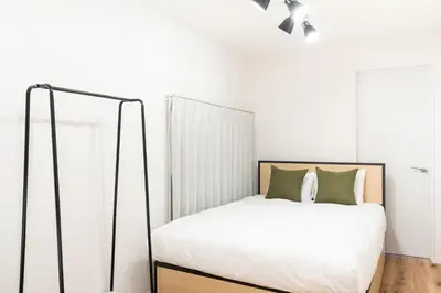 a bedroom with a bed with white sheets and green pillows at \u4eac\u5cf63\u4e01\u76ee\u8cb8\u6238\u5efa in Tokyo