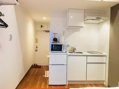 a small white kitchen with a microwave and a stove at Okubo House 3F SJ0277 in Tokyo