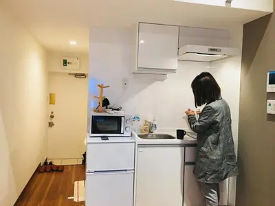 a woman standing in a kitchen with a sink at Okubo House 3F SJ0277 in Tokyo