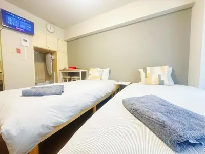 two beds in a room with a clock on the wall at \u65b0\u5bbf\u5e02\u4e2d\u5fc3\u6b4c\u821e\u4f0e\u753a\u4f0a\u52bf\u4e39\u5f92\u6b653\u5206\u949f#1 in Tokyo